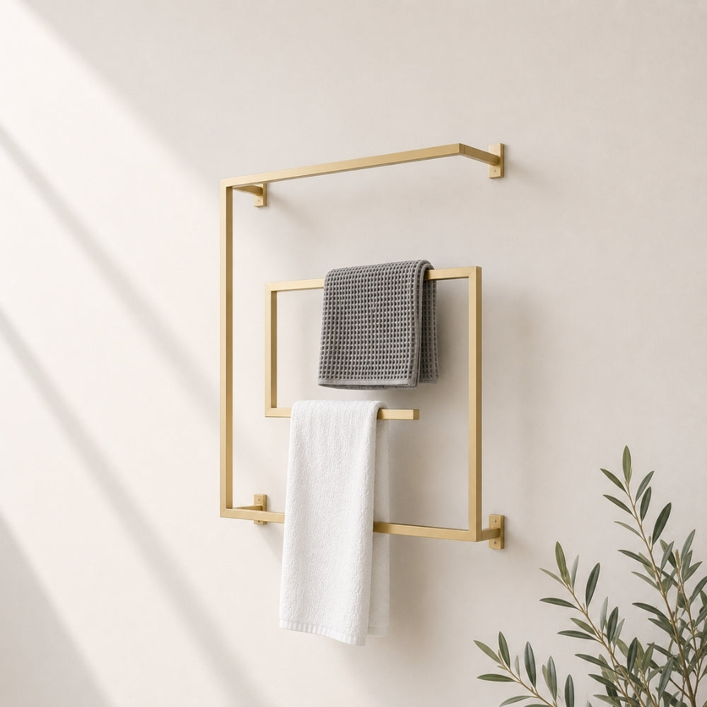 Gold wall mounted square swivel towel rack holding gray and white towels on a bathroom wall.