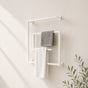 White wall mounted square swivel towel rack holding gray and white towels on a bathroom wall.
