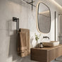 Black wall mounted staggered towel rack with beige towels beside a modern bathroom vanity.