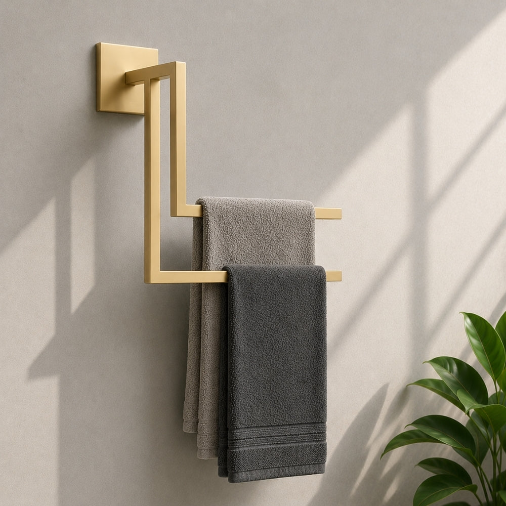 Gold wall mounted staggered towel rack holding gray towels on a bathroom wall.
