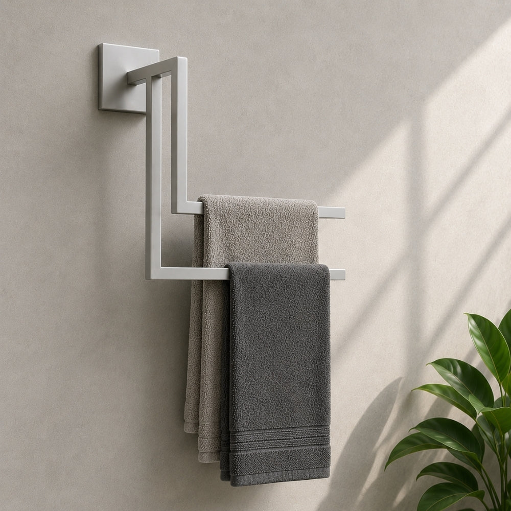 White wall mounted staggered towel rack angle view holding gray towels beside a green plant.