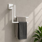 White wall mounted staggered towel rack holding gray towels on a bathroom wall.