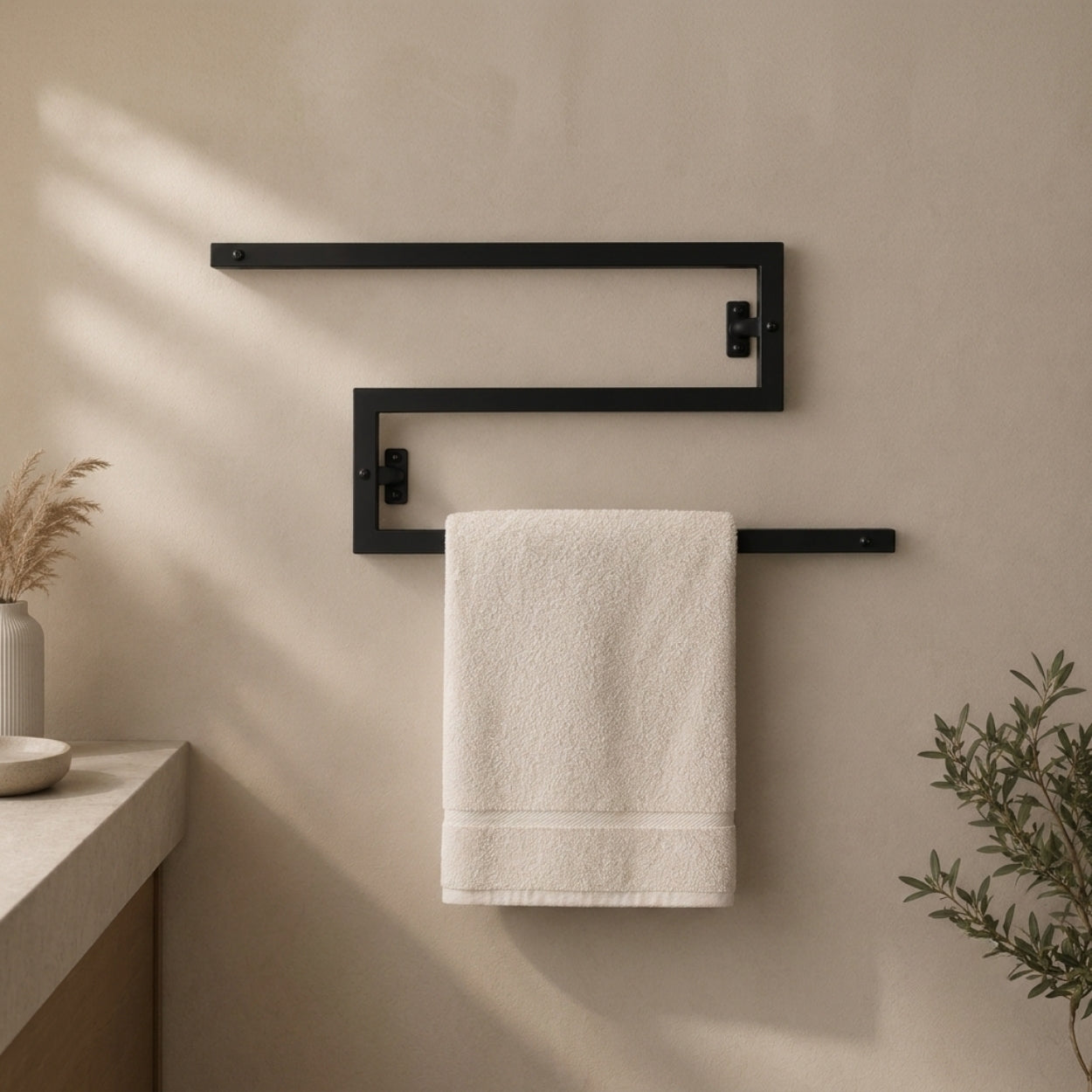 Black wall mounted zigzag swivel towel rack holding a towel.