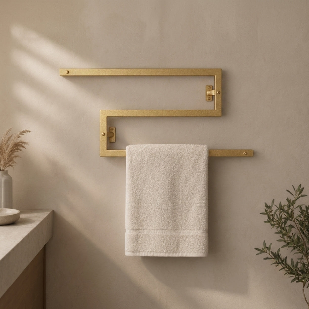 Gold wall mounted zigzag swivel towel rack holding a towel.