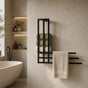 Black wall mounted towel rack with storage shelf holding rolled towels and a hanging towel in a modern bathroom.