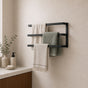 Black wall mounted triple towel bar rack with three towels in a modern bathroom.