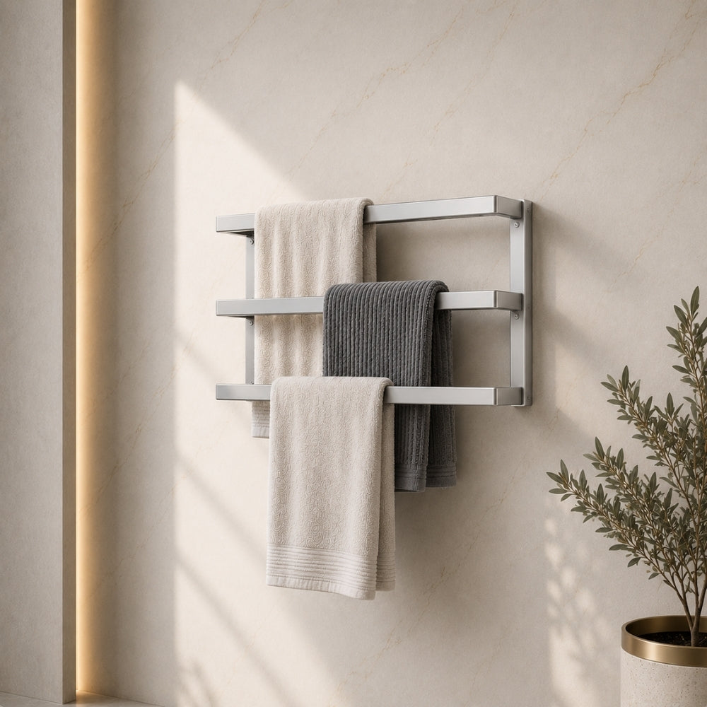 Satin nickel wall mounted triple towel bar rack holding three towels on a marble-look bathroom wall.