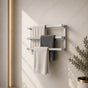 Satin nickel wall mounted triple towel bar rack holding three towels on a marble-look bathroom wall.