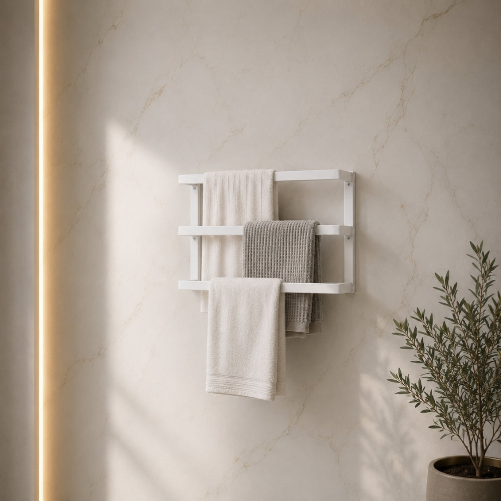 White wall mounted triple towel bar rack holding three towels on a marble-look bathroom wall.