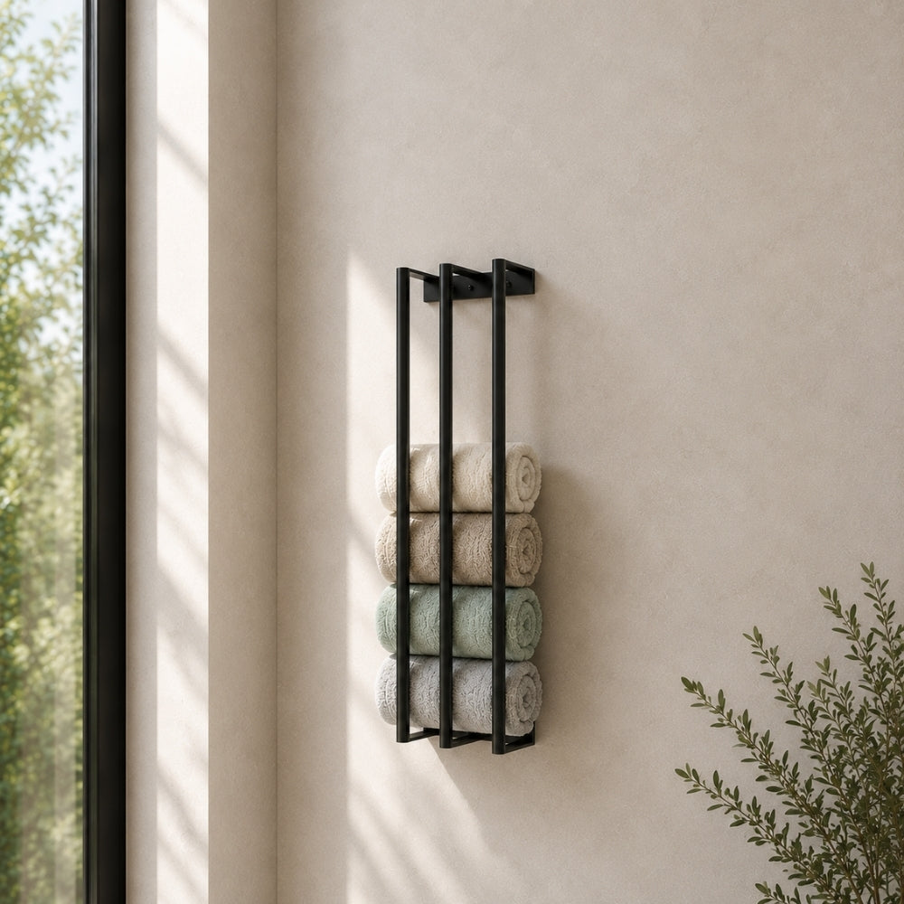 Black wall mounted vertical towel rack with rolled towels beside a bathroom window.
