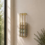 Gold wall mounted vertical towel rack with rolled towels in a light bathroom.