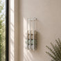 White wall mounted vertical towel rack with rolled towels in a light bathroom.