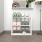 A white metal slipper rack with two pairs of white and green slippers, set against a neutral wall with a wooden floor for a clean, modern look