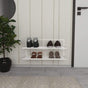A white wall-mounted shoe rack with two tiers holding boots, sneakers, and heels, placed in an entryway with a potted plant, a circular mirror, and a beige paneled wall.